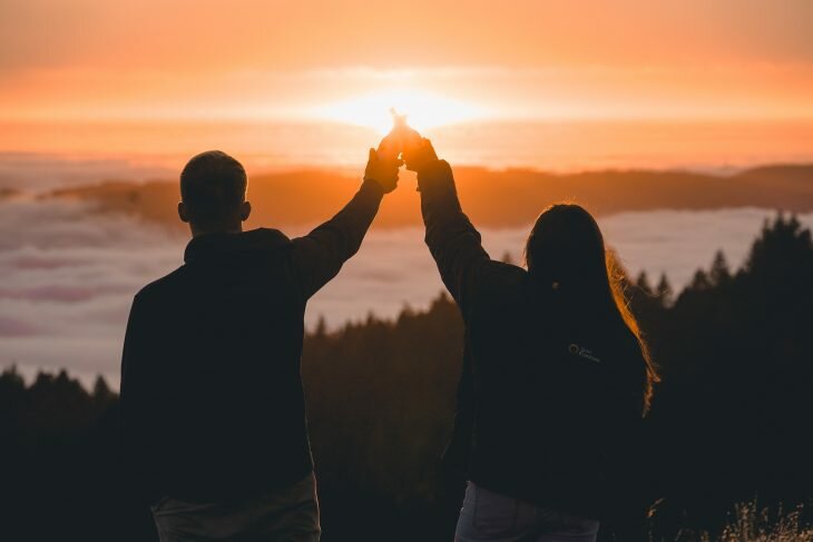 Man and woman raising glasses towards the sunset.